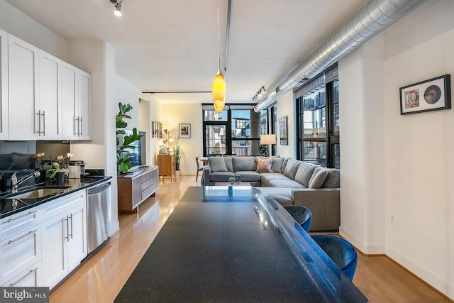 kitchen with a sink, white cabinets, light wood-type flooring, dishwasher, and dark countertops