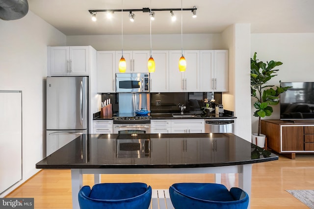 kitchen with stainless steel appliances, a breakfast bar, white cabinets, and a sink