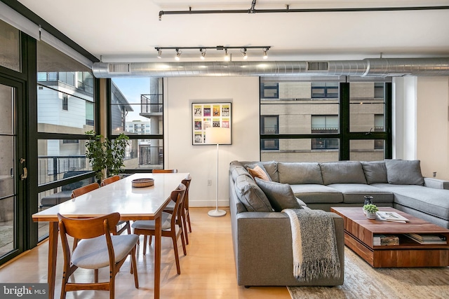 living area with light wood finished floors, a wall of windows, rail lighting, and visible vents