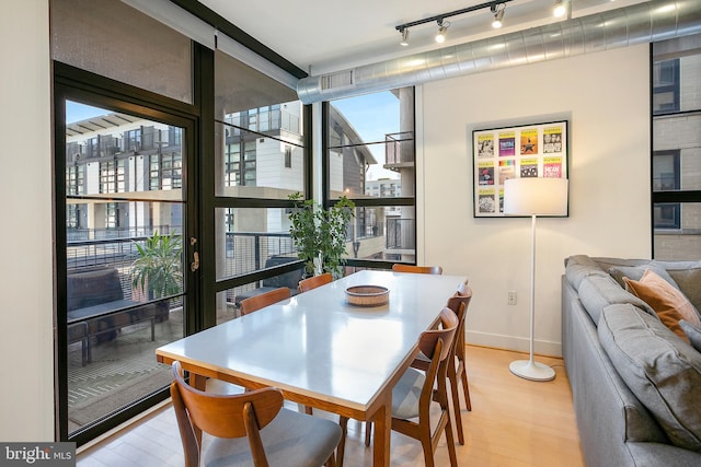 dining area featuring expansive windows, light wood-type flooring, visible vents, and track lighting