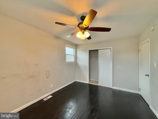 unfurnished bedroom with dark hardwood / wood-style flooring, a closet, and ceiling fan