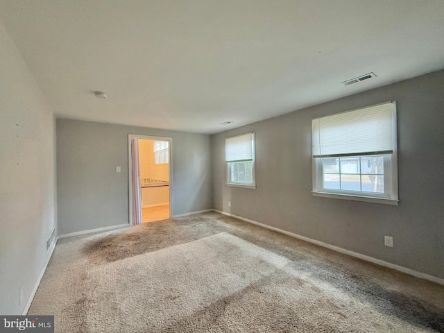 unfurnished bedroom featuring ensuite bath and carpet floors