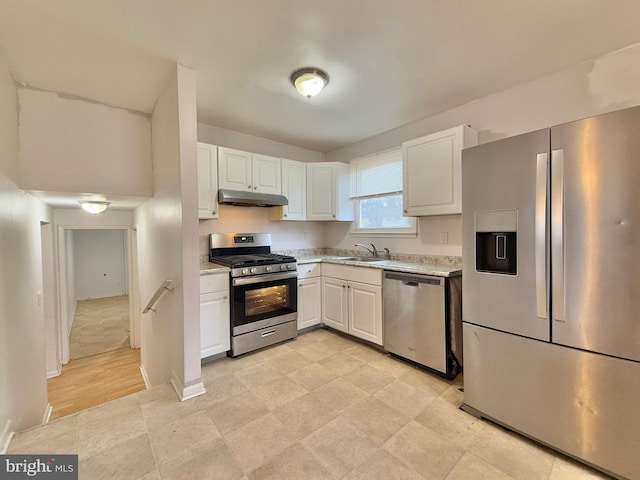 kitchen featuring white cabinets, appliances with stainless steel finishes, light stone countertops, and sink