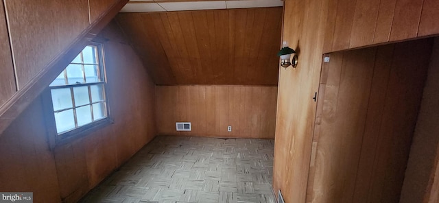 additional living space with light parquet floors, wooden walls, and vaulted ceiling