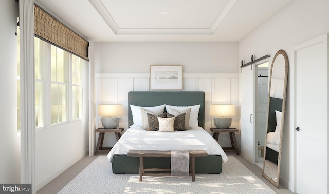 carpeted bedroom with a barn door, a raised ceiling, and multiple windows