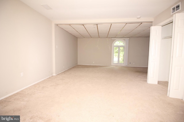 unfurnished room featuring a paneled ceiling and light colored carpet