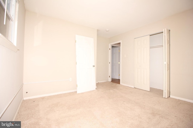 unfurnished bedroom with a closet and light colored carpet