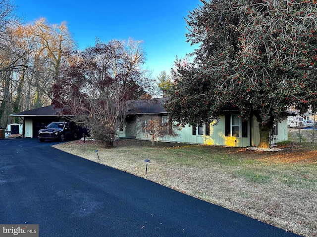 view of property hidden behind natural elements featuring a carport and a front lawn