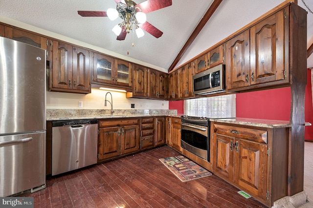 kitchen with vaulted ceiling, dark hardwood / wood-style floors, stainless steel appliances, ceiling fan, and sink