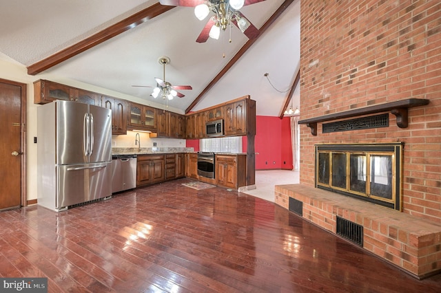 kitchen with stainless steel appliances, dark wood-type flooring, a brick fireplace, high vaulted ceiling, and beam ceiling