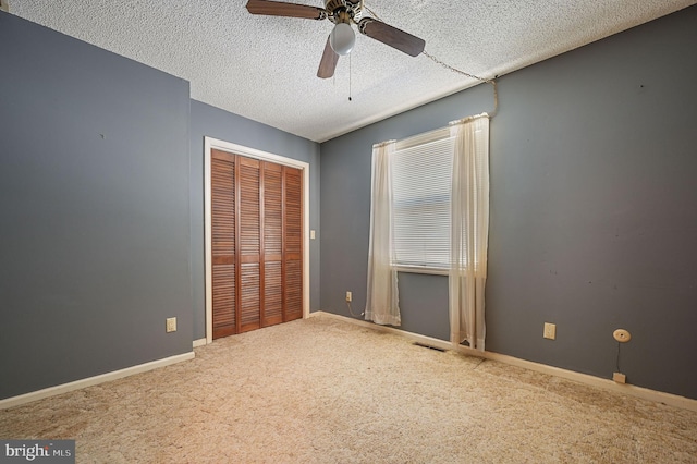 unfurnished bedroom with ceiling fan, a closet, carpet, and a textured ceiling