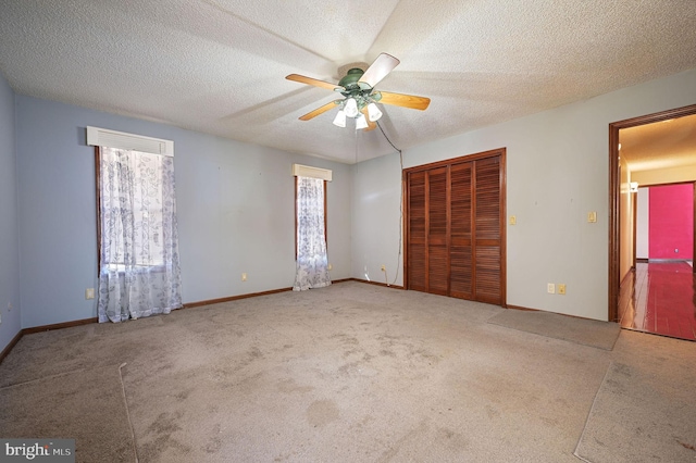 unfurnished bedroom featuring a textured ceiling, carpet floors, ceiling fan, and multiple windows