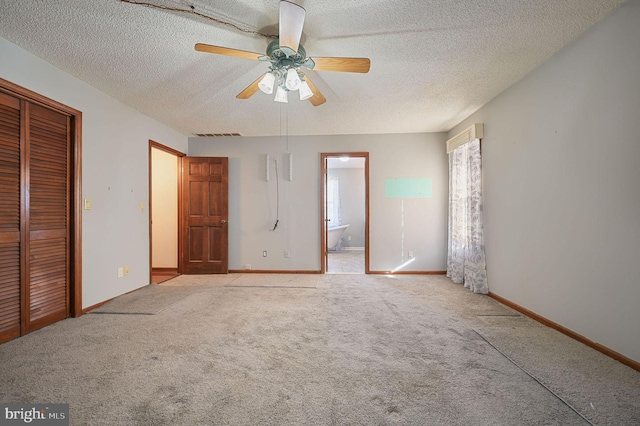 unfurnished bedroom with a closet, ensuite bath, light carpet, ceiling fan, and a textured ceiling