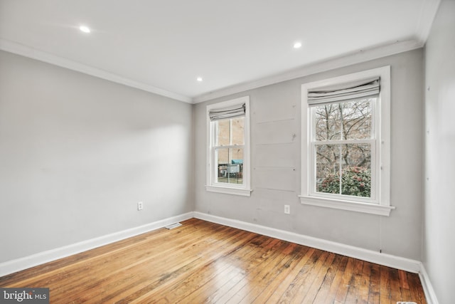 empty room featuring wood-type flooring, ornamental molding, and a healthy amount of sunlight