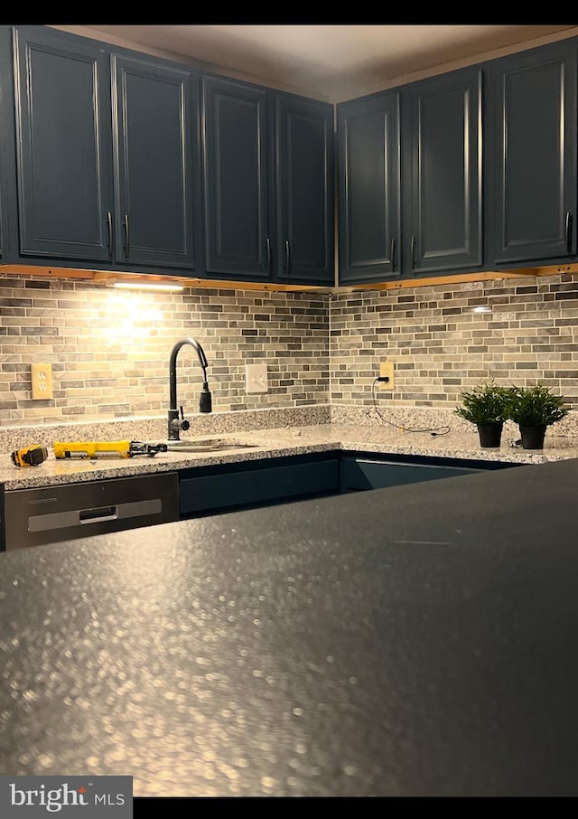 kitchen featuring light stone countertops, sink, and tasteful backsplash