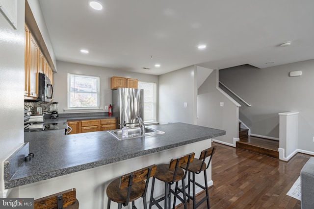 kitchen featuring sink, stainless steel refrigerator, stove, a kitchen bar, and kitchen peninsula