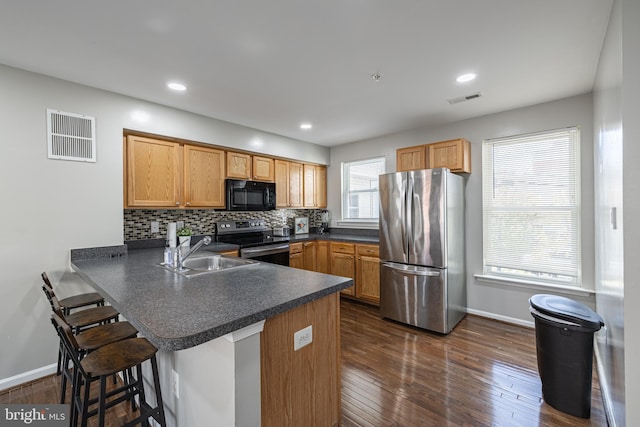 kitchen with sink, a breakfast bar area, kitchen peninsula, and appliances with stainless steel finishes