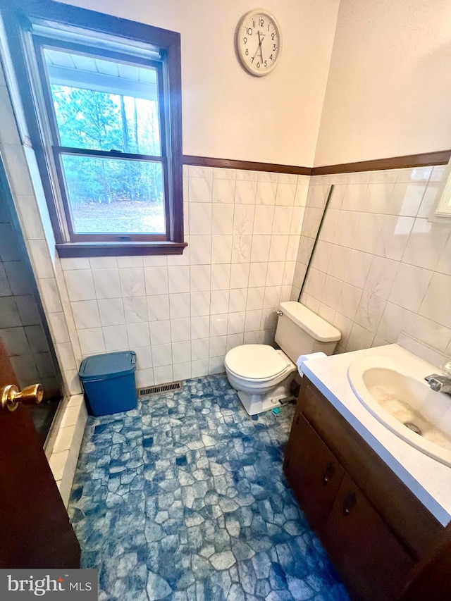 bathroom featuring vanity, toilet, and tile walls