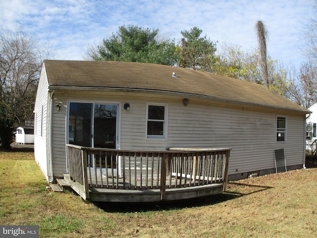 rear view of house featuring a deck and a lawn