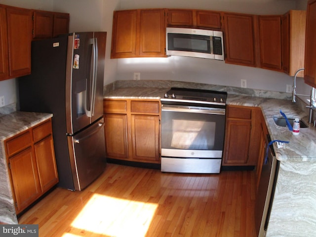 kitchen with stainless steel appliances, light hardwood / wood-style flooring, and sink