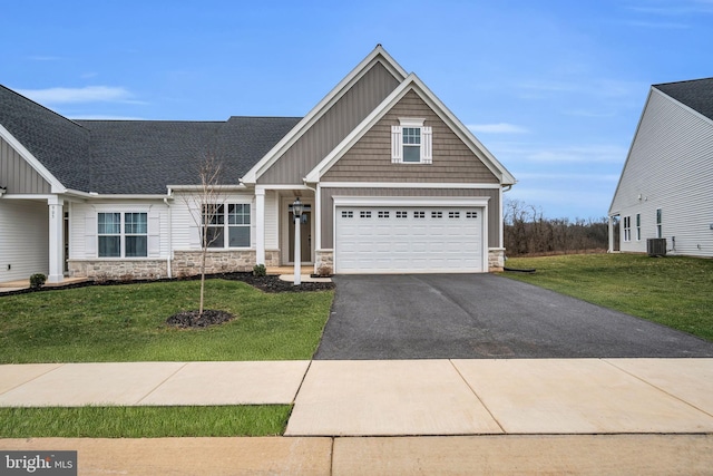 craftsman inspired home featuring a front yard, a garage, and central AC unit