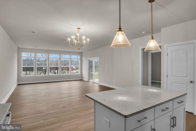 kitchen with white cabinetry, an inviting chandelier, light hardwood / wood-style flooring, decorative light fixtures, and a kitchen island