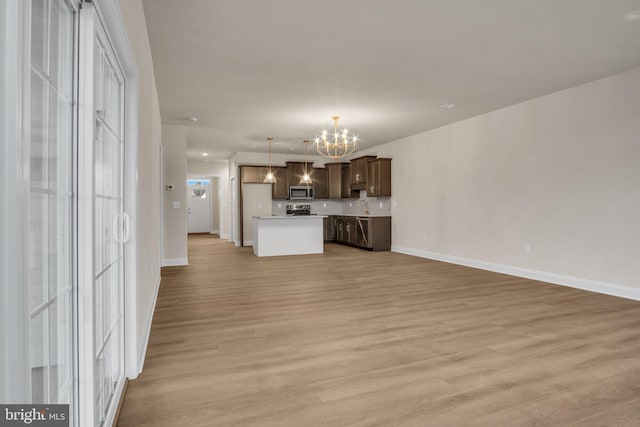 unfurnished living room with light hardwood / wood-style flooring, a chandelier, and sink