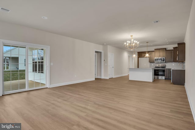 unfurnished living room with a chandelier and light hardwood / wood-style floors