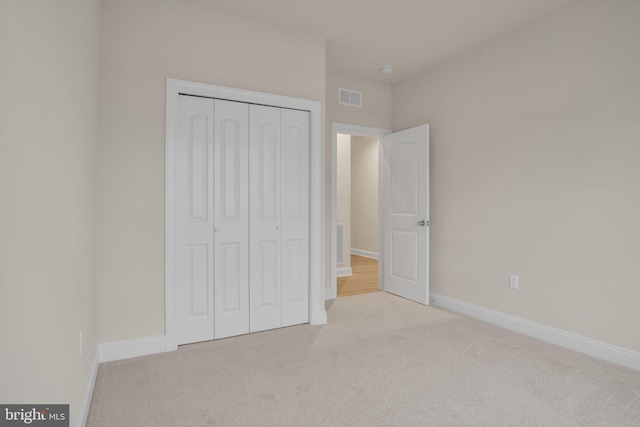 unfurnished bedroom featuring light colored carpet and a closet