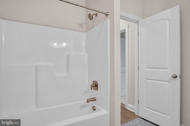 bathroom with hardwood / wood-style floors and washtub / shower combination