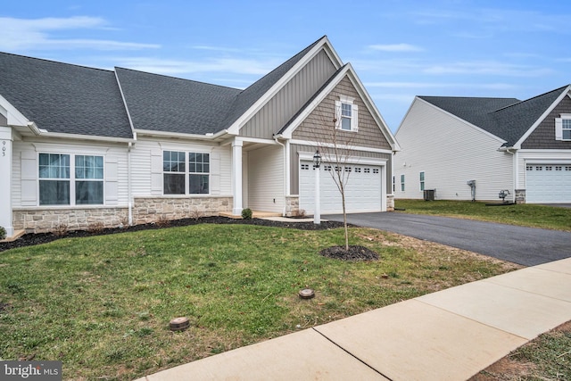 view of front of home featuring a front yard, central AC, and a garage