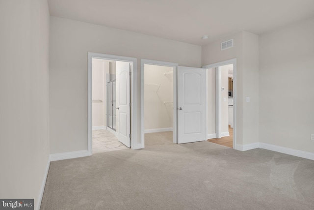 unfurnished bedroom with light colored carpet, a spacious closet, and a closet