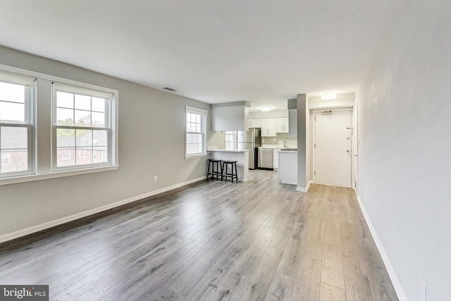 unfurnished living room with a healthy amount of sunlight and light hardwood / wood-style flooring