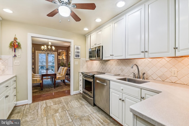 kitchen featuring white cabinets, appliances with stainless steel finishes, ceiling fan with notable chandelier, and sink