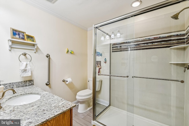 bathroom featuring ornamental molding, vanity, hardwood / wood-style floors, toilet, and a shower with shower door