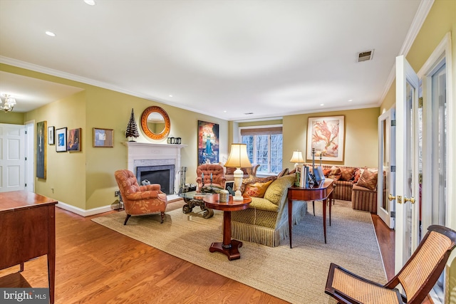 living room featuring a premium fireplace, ornamental molding, and light hardwood / wood-style flooring