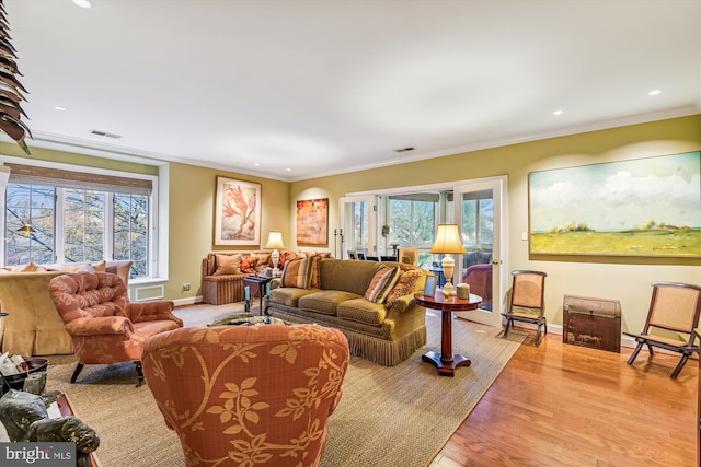 living room featuring light hardwood / wood-style flooring, a healthy amount of sunlight, and ornamental molding