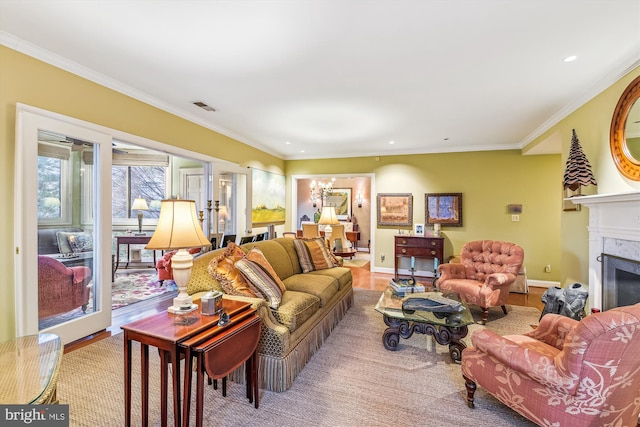 living room featuring a notable chandelier, a premium fireplace, crown molding, and light hardwood / wood-style flooring