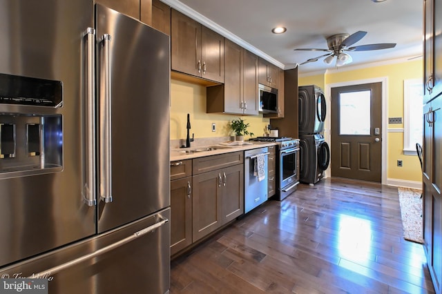 kitchen featuring sink, ceiling fan, dark hardwood / wood-style floors, stacked washer / drying machine, and premium appliances