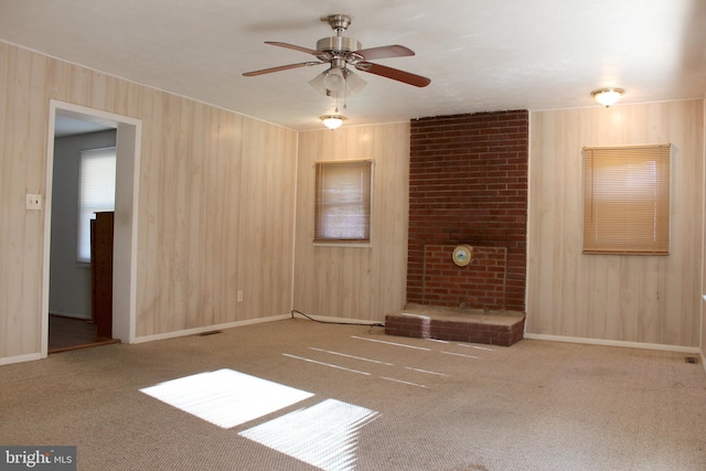 carpeted spare room featuring ceiling fan and wood walls