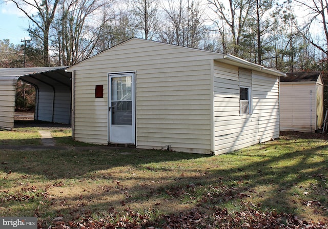 view of outdoor structure with a lawn and a carport