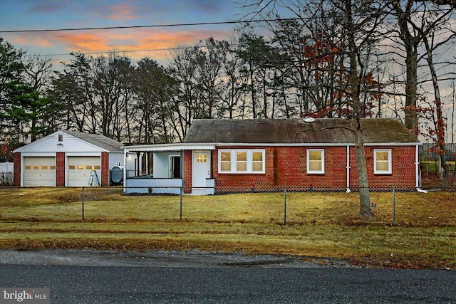 view of front of home featuring a lawn, an outbuilding, covered porch, and a garage