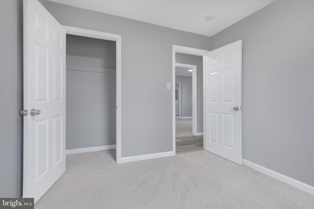 unfurnished bedroom featuring light colored carpet and a closet