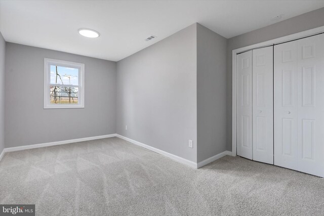 unfurnished bedroom with light carpet and a closet