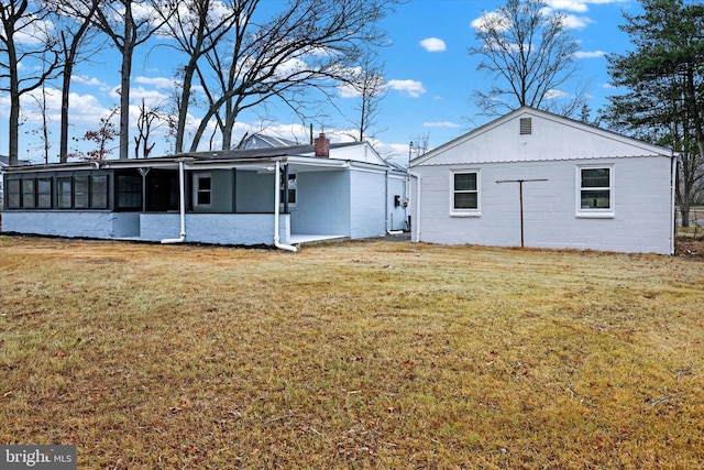 back of house featuring a lawn and a sunroom