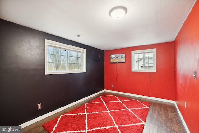 empty room with plenty of natural light and dark wood-type flooring