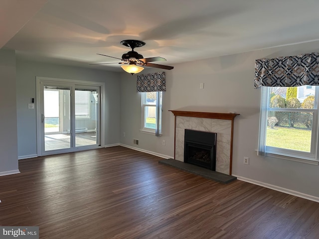 unfurnished living room with ceiling fan, dark hardwood / wood-style flooring, and a tiled fireplace