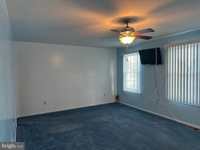 spare room featuring dark carpet and ceiling fan