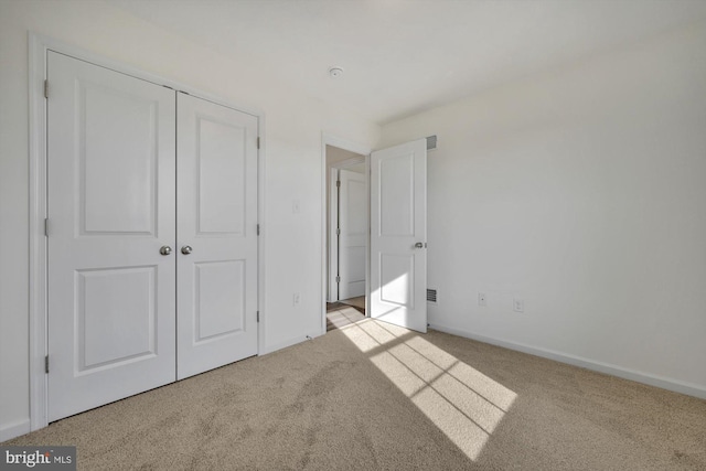 unfurnished bedroom with light colored carpet and a closet