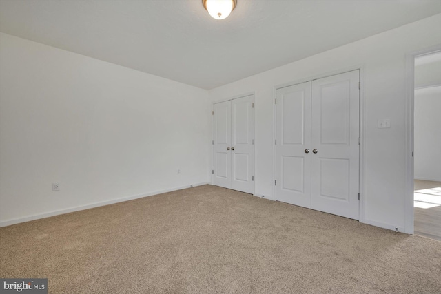 unfurnished bedroom featuring multiple closets and light colored carpet